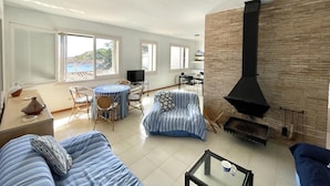 A spacious living area with a fireplace, a dining table, and a sofa. - Sa Tuna - House with Views and 30m from the Sea (Begur)