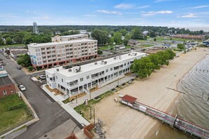 A multi-story hotel with a central courtyard, located near a beach with a pier. - Luxurious 3 Bedroom Riverfront Condo with Private Deck (Colonial Beach)