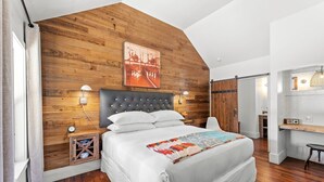Een slaapkamer met een slaapdak, een bed met witte lakens, een sprei en een nachtkastje met een lamp.