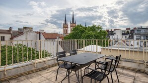 A rooftop terrace with a table and chairs, a view of a church spire, and surrounding buildings. - Delightful Josefstadt 3BR, Furnished + Open Design, by Blueground (Vienna)