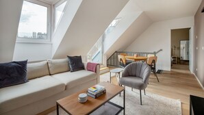 A modern loft apartment with a high ceiling, a dining area, and a staircase leading to an upper floor. - Delightful Josefstadt 3BR, Furnished + Open Design, by Blueground (Vienna)