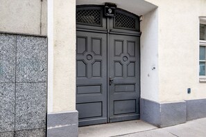 Eine Doppeltür mit einer Nummertafel, eine Steinsäule und ein kleines Fenster.