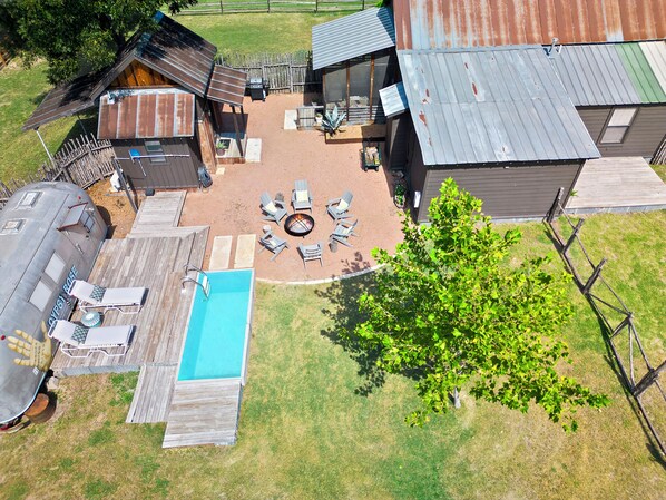 A residential property with a swimming pool, outdoor seating area, and a fire pit.