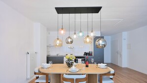 A modern dining area with a wooden table, white chairs, and a vase of flowers. - Chic and Spacious 2Room Apartment in Wuppertal Center with Free WiFi and Kitchen (Wuppertal)