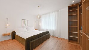 A bedroom with a large bed, wooden floor, white walls, and a wooden wardrobe. - Chic and Spacious 2Room Apartment in Wuppertal Center with Free WiFi and Kitchen (Wuppertal)