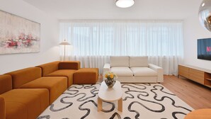 A modern living room with a sofa, ottoman, coffee table, and artwork on the wall. - Chic and Spacious 2Room Apartment in Wuppertal Center with Free WiFi and Kitchen (Wuppertal)