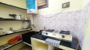 A compact kitchen with a gas stove, a water dispenser, and a gas cylinder. - Feel at Home: Exceptional Comfort and Convenience! (Chennai)