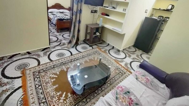 A compact hotel room with a bed, a small desk, a TV, a wardrobe, and a bathroom with a shower curtain. - Feel at Home: Exceptional Comfort and Convenience! (Chennai)