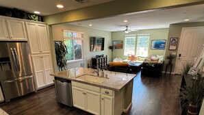 Una cocina amplia con una isla central, armarios blancos y un refrigerador de acero inoxidable.