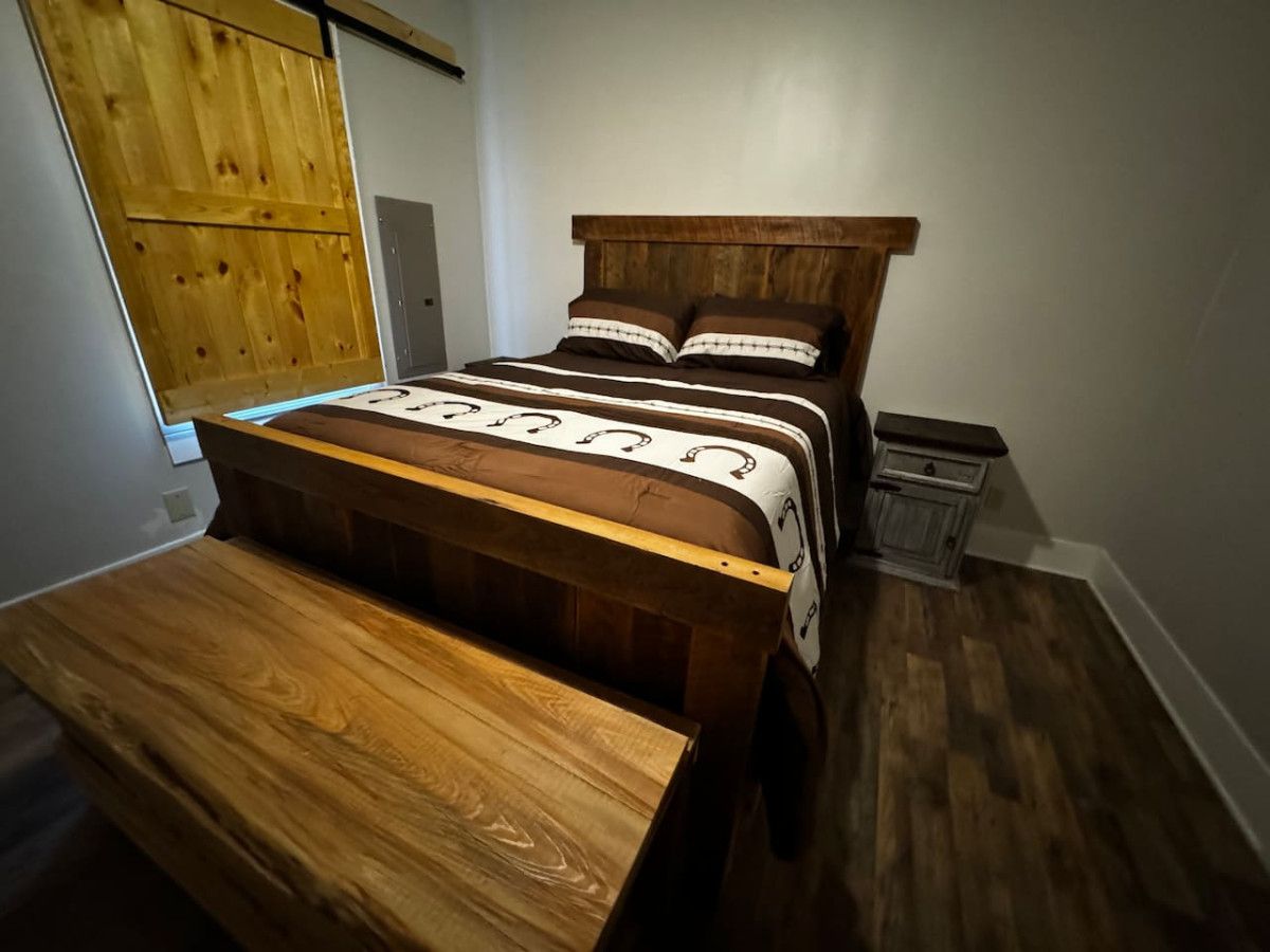 A bedroom with a wooden bed, a wooden bench, and a small cabinet.