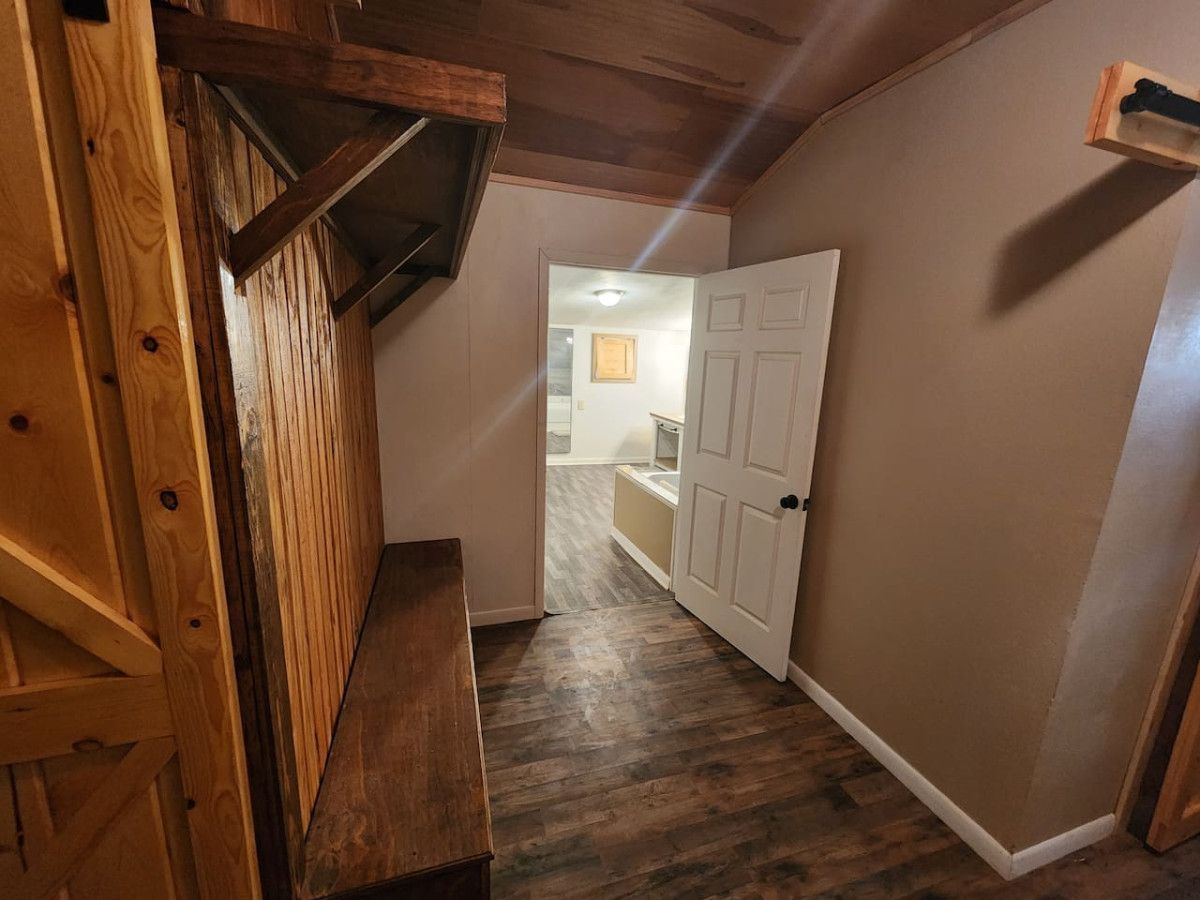 A hallway with wooden beams, a bench, and a door leading to a bathroom.