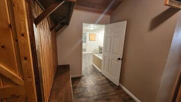 A hallway with wooden beams, a bench, and a door leading to a bathroom.