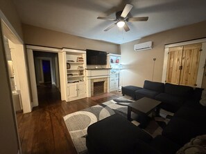 Un salon avec une cheminée, un ventilateur de plafond et un téléviseur.