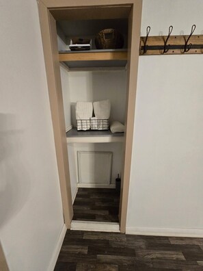 A narrow hallway leading to a closet with shelves, a basket, and a coat rack. - Messick Farmstyle Home (Marksville)