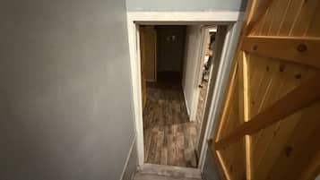 A narrow stairway leading to a room with a wooden floor and a door with a wooden frame.