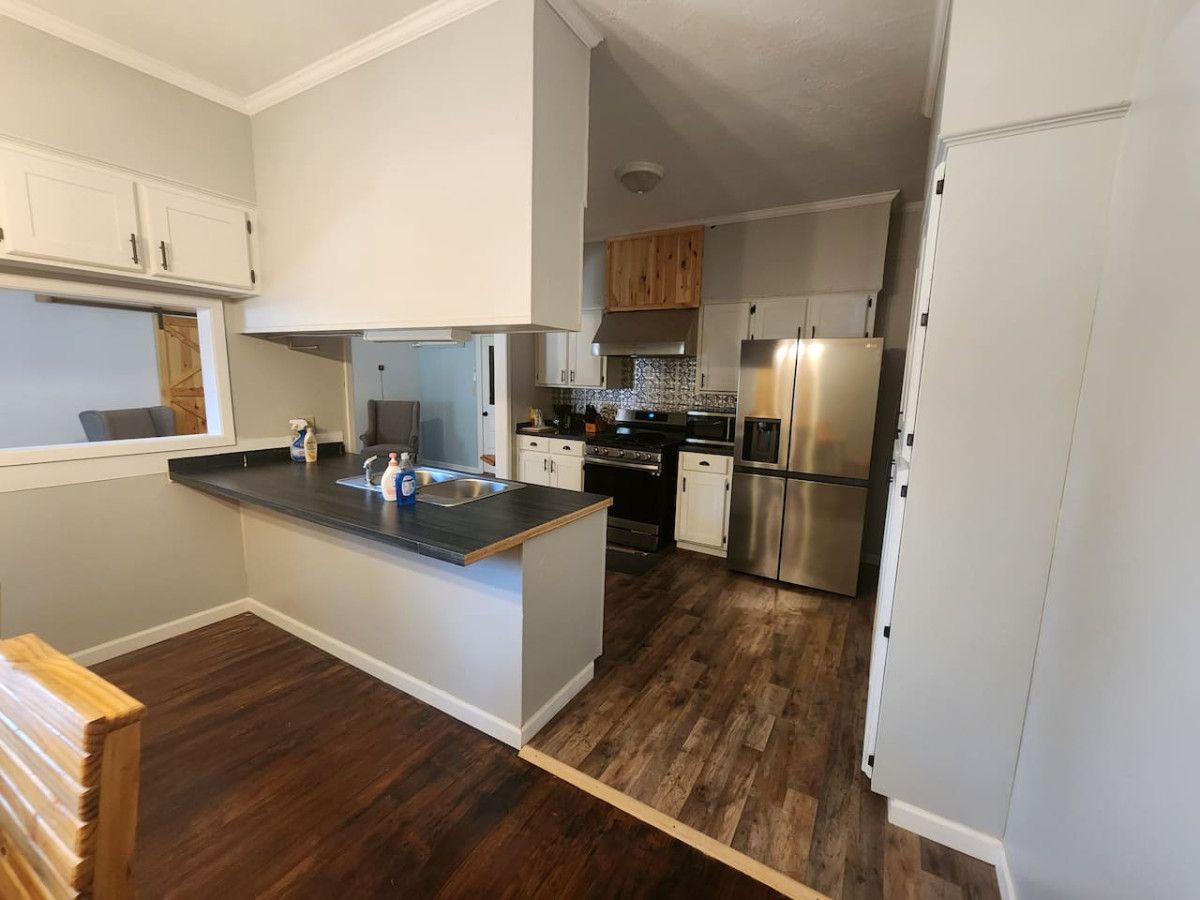 Una cocina moderna con armarios blancos, electrodomésticos de acero inoxidable y una isla central.