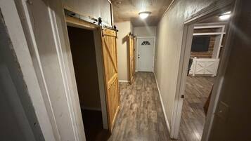 A narrow hallway with wooden flooring, a sliding barn-style door, and a white door at the end.