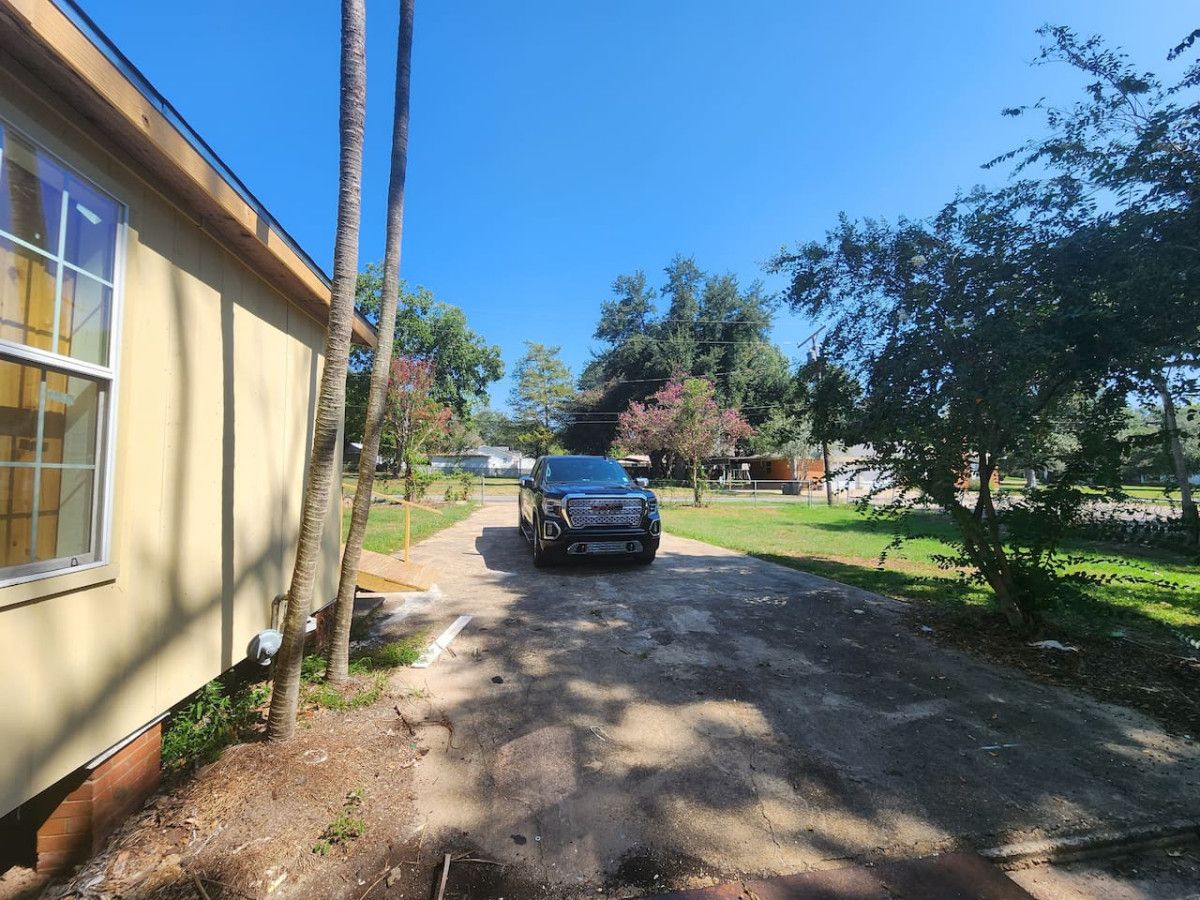 A vehicle parked on a dirt path beside a building with a window.
