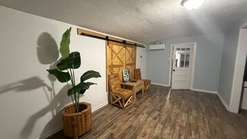 A room with wooden flooring, a sliding barn door, a potted plant, and a small table with chairs.