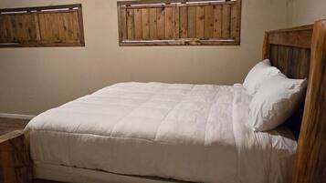 A single bed with a wooden headboard and footboard, a ceiling fan, and a wall-mounted air conditioning unit.