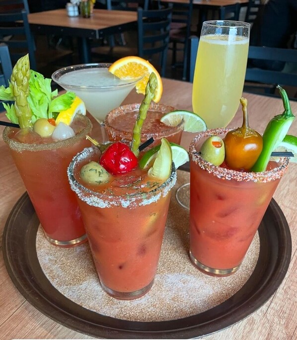 A tray with three drinks, each garnished with different ingredients, and a glass of iced tea.