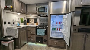 A compact kitchen with a built-in microwave, a stainless steel refrigerator, a stove, and a sink.
