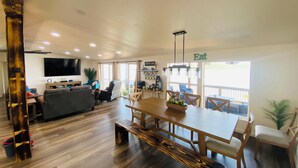A spacious living area with a wooden dining table, comfortable seating, a flat-screen TV, and a coffee bar.