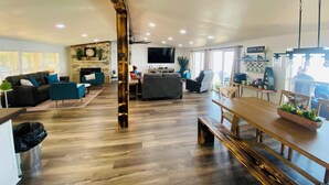 A spacious living area with a stone fireplace, a coffee bar, and a large TV screen.