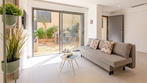 Ein modernes Wohnzimmer mit einer Couch, einem kleinen runden Tisch und einem Blumentopf.