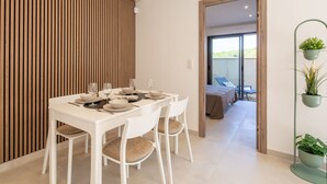 Ein Essbereich mit einem weißen Tisch, gedeckt für sechs Personen, weißen Stühlen und einer Wand aus Holzlatten.