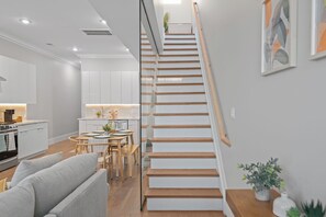 Un intérieur moderne comprenant un escalier, une cuisine, un coin repas et un espace de vie.