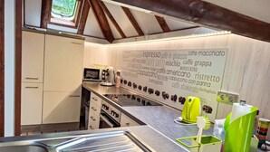 Une cuisine avec un plafond en bois, un four à micro-ondes, une machine à café et un mur orné de mots liés au café.