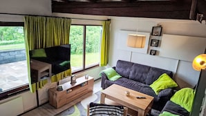 Un salon confortable avec un canapé, une table basse, un téléviseur et un meuble en bois.