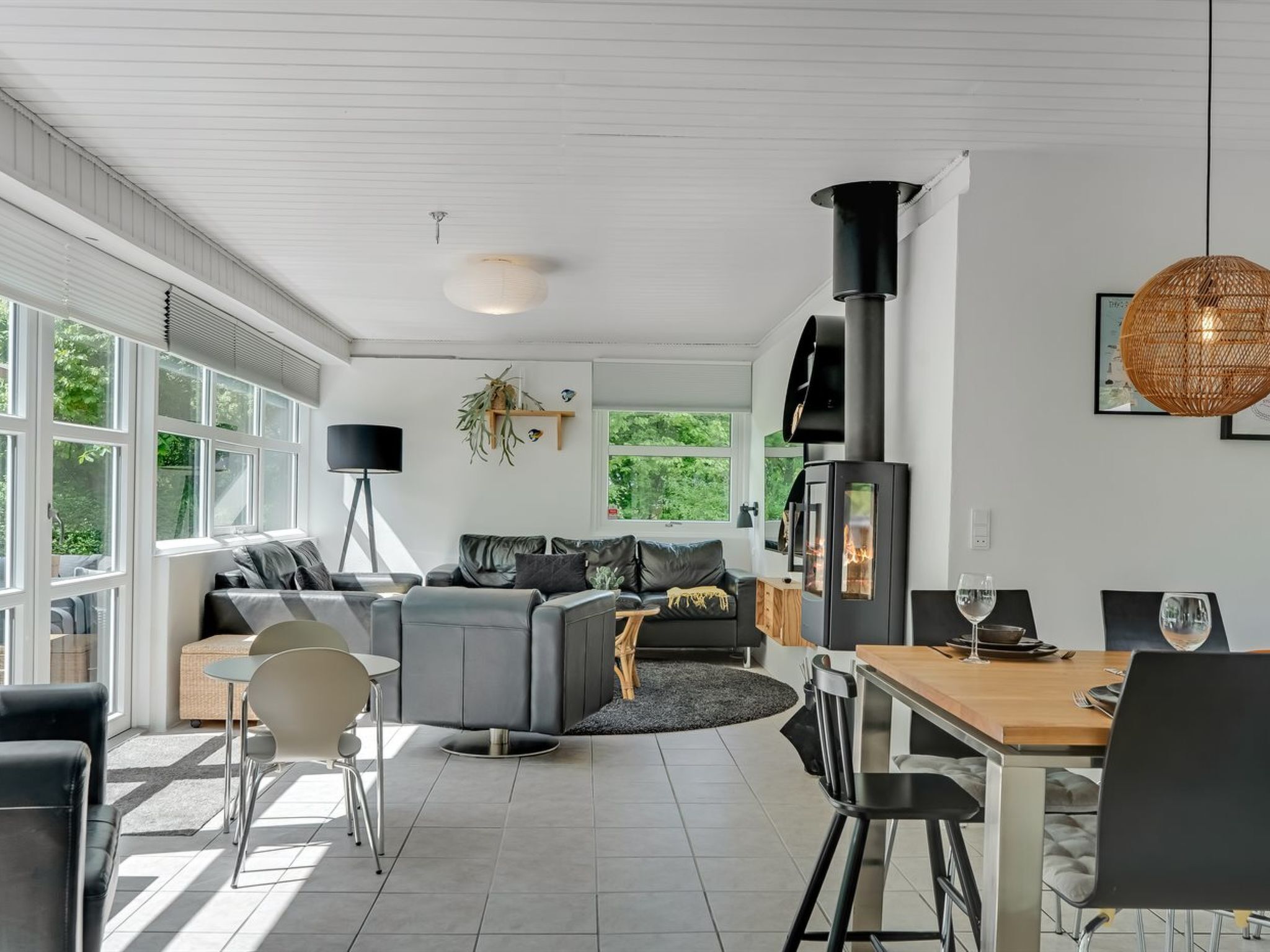 A modern living room with a fireplace, a dining area with a table and chairs, and a sofa set.