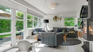 Un salon moderne doté d’une cheminée, de grandes fenêtres et d’un coin repas.