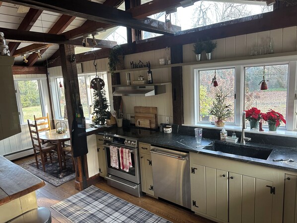A kitchen with wooden beams, a stove, oven, and a sink. There are Christmas decorations and a window with a view of trees. - 1798 House - Historic house 1 mile from downtown New Hope (New Hope)