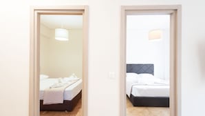 Een hotelkamer met twee bedden, houten vloeren en een lichtgekleurde muur.