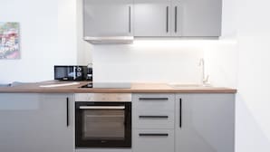 Een moderne keuken met witte kasten, een inbouwoven, een magnetron en een spoelbak.