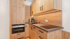 A modern kitchen with wooden cabinets, a stainless steel sink, and a built-in oven. - Moderne Ferienwohnung (Großarl)