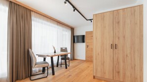 A modern room with a wooden wardrobe, a dining table with chairs, and a TV mounted on the wall. - Moderne Ferienwohnung (Großarl)