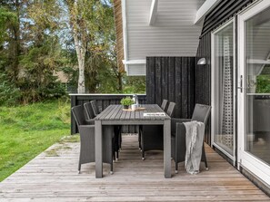 Eine Terrasse mit Tisch und Stühlen, umgeben von viel Grün.