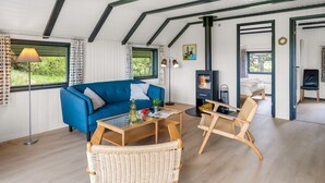 A room with a blue sofa, wicker chairs, a table, a fireplace, and a view of greenery outside. - "Gyrial" - 2km from the sea by Interhome (Blåvand)