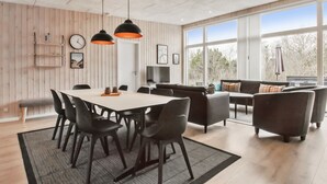 Una sala de estar moderna con comedor, ventanas amplias y televisión.