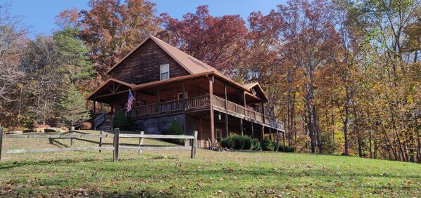 A wooden cabin with a balcony, surrounded by autumn trees. - Rustic Elegance Lodge - Picturesque 6 bedroom cabin, Hot Tub, Pool Table (NASHVILLE)