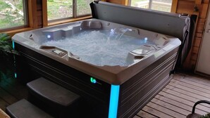 Ein Whirlpool mit Bedienfeld und einer Stufe, umgeben von Holzwänden und Fenstern.
