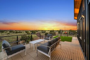 A deck with outdoor furniture, a table, and a view of the sunset. - NEW Luxe Ranch Double Villas Near GC S Rim (Williams)