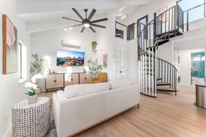 A modern living room with a sofa, a TV, a ceiling fan, and a staircase. - NEW Luxe Ranch Double Villas Near GC S Rim (Williams)
