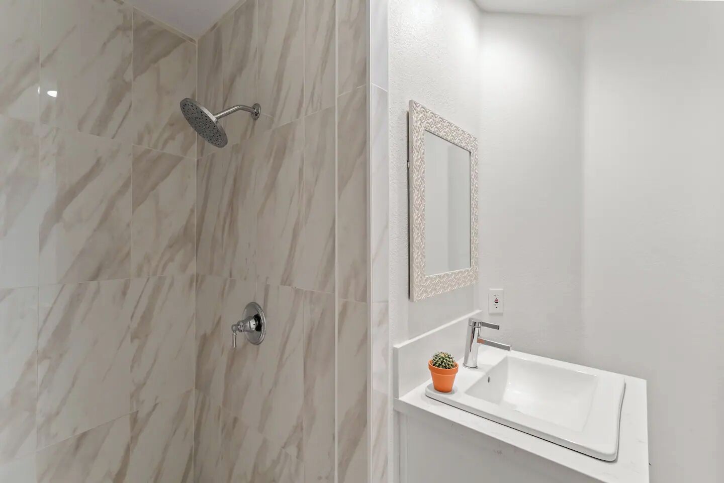 Un baño con ducha, lavamanos y espejo.