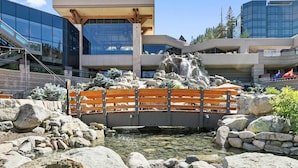 Un edificio moderno con fachada de vidrio y un puente sobre una pequeña fuente de agua.