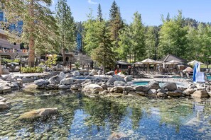 Une zone de villégiature avec une piscine aux eaux cristallines, entourée de rochers, de chaises longues et d’un belvédère.
